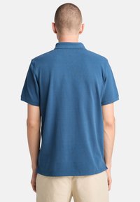 Blå pikétröja i mjukt tyg, med korta ärmar, klassisk krage och en ren, avslappnad passform.