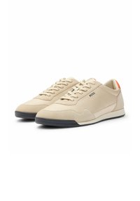 Sneakers beige realizzati in camoscio e tessuto, con un design con lacci, un accento arancione contrastante sul tallone e una suola in gomma nera.