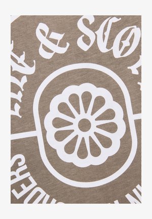 Wit bloemmotief met afgeronde bloemblaadjes binnen een ovaal, omringd door gedeeltelijke witte tekst op een beige stoffen achtergrond met textuur.