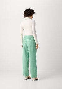 Lightweight, fitted white turtleneck and loose, mint-green pants with an elastic waistband. Smooth texture and simple design.