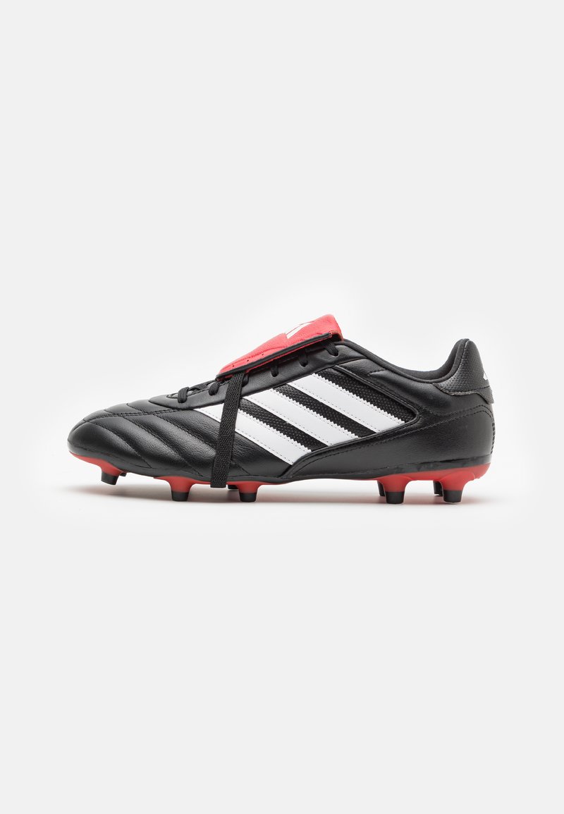 Chaussure de football noire avec un design à trois bandes blanches, présentant un accent rouge sur le languette supérieure, un dessus en synthétique texturé et des crampons moulés.