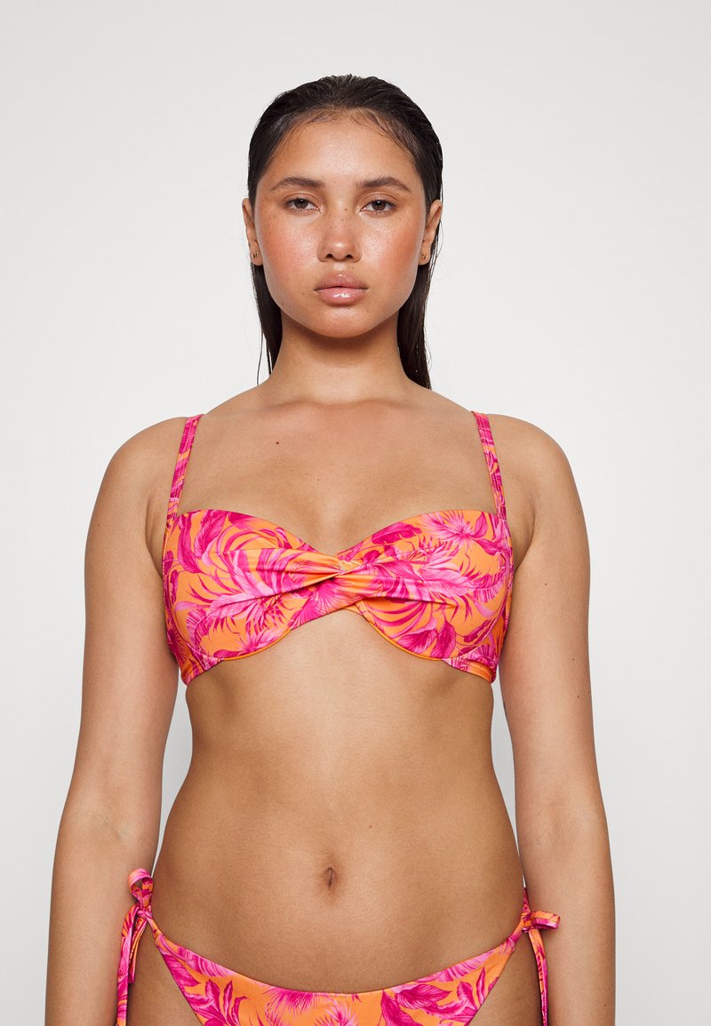 Conjunto de biquíni floral com um design de frente torcida. Tecido laranja vivo com padrões de folhas rosa. Alças ajustáveis e laços laterais nos calções.