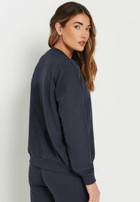 Donkerblauwe sweatshirt met een ontspannen pasvorm, geribde cuffs en onderrand. Heeft een ronde halslijn en zachte, gestructureerde stof.