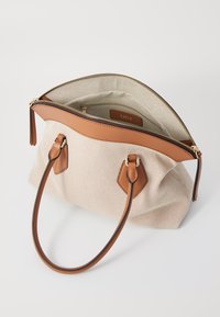 Beige canvas handtas met bruin leren accenten, een ritssluiting en dubbele bovenhandvaten; gevoerde binnenkant met een pocket.