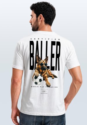 Man wearing a white t-shirt with a graphic of a dog wearing sunglasses pawing a soccer ball and large text reading "Certified Baller."