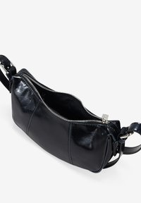 Bolso cruzado de cuero negro con abertura con cremallera, textura suave, correa ajustable y forma rectangular. Presenta herrajes plateados.