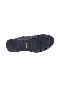 Suola di scarpa in gomma nera con battistrada a motivo, dotata di un emblema dorato al centro. Composta di materiale resistente, progettata per garantire trazione.