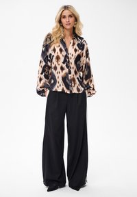Animal print blouse in shades of brown, black, and cream; relaxed fit with button closure. Wide black trousers with a flowy silhouette.