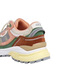 Basket multicolore présentant un mélange de matériaux comprenant du mesh, du daim et du caoutchouc. Les couleurs incluent vert, pêche, gris et des tons neutres.