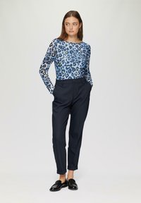 Blauwe luipaardprint lange mouwen top, gecombineerd met zwarte op maat gemaakte broeken, met een strakke textuur en een slim fit ontwerp. Zwarte instappers maken de look compleet.