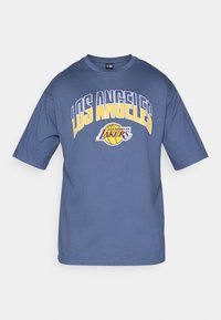 Modra bombažna majica s kratkimi rokavi, na kateri je v rumeni in beli barvi napis "LOS ANGELES" ter logotip Lakers v vijolični barvi.