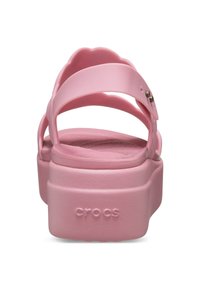 Sandales en caoutchouc roses avec un design à plateforme, dotées d'accents de larges sangles et de détails moulés sur le talon. Logo « CROCS » sur le côté.
