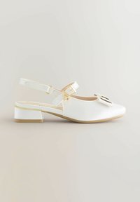 Fehér slingback cipő alacsony, szögletes sarokkal. Simább szatén felületí, masni részlettel és arany színű fémes díszítésekkel.