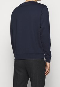 Sudadera de color marino con mangas largas, cuello redondo y puños acanalados. Tejido suave con una textura lisa; corte relajado y dobladillo.