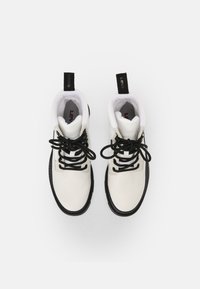 White leather high-top sneakers with black laces, black sole, and black accents, featuring a prominent logo on the tongue and pull tabs.