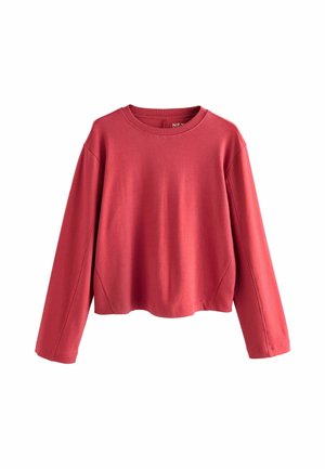 Röd långärmad bomullspullover med rund hals och avslappnat axeldropp. Slät textur och en avslappnad passform, med sido-seams accentuerade.
