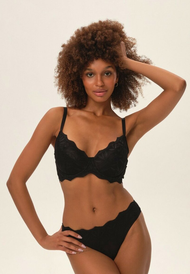 Czarny koronkowy stanik i dopasowane majtki z wysokim stanem o falbaniastych brzegach. Zawiera kwiatowy haft i cienkie regulowane ramiączka. Gładka tekstura.