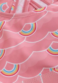 Rosa simkläder tyg med en scallop-mönster och multicolorer regnbågsaccent. Slät textur med sömmade kanter.