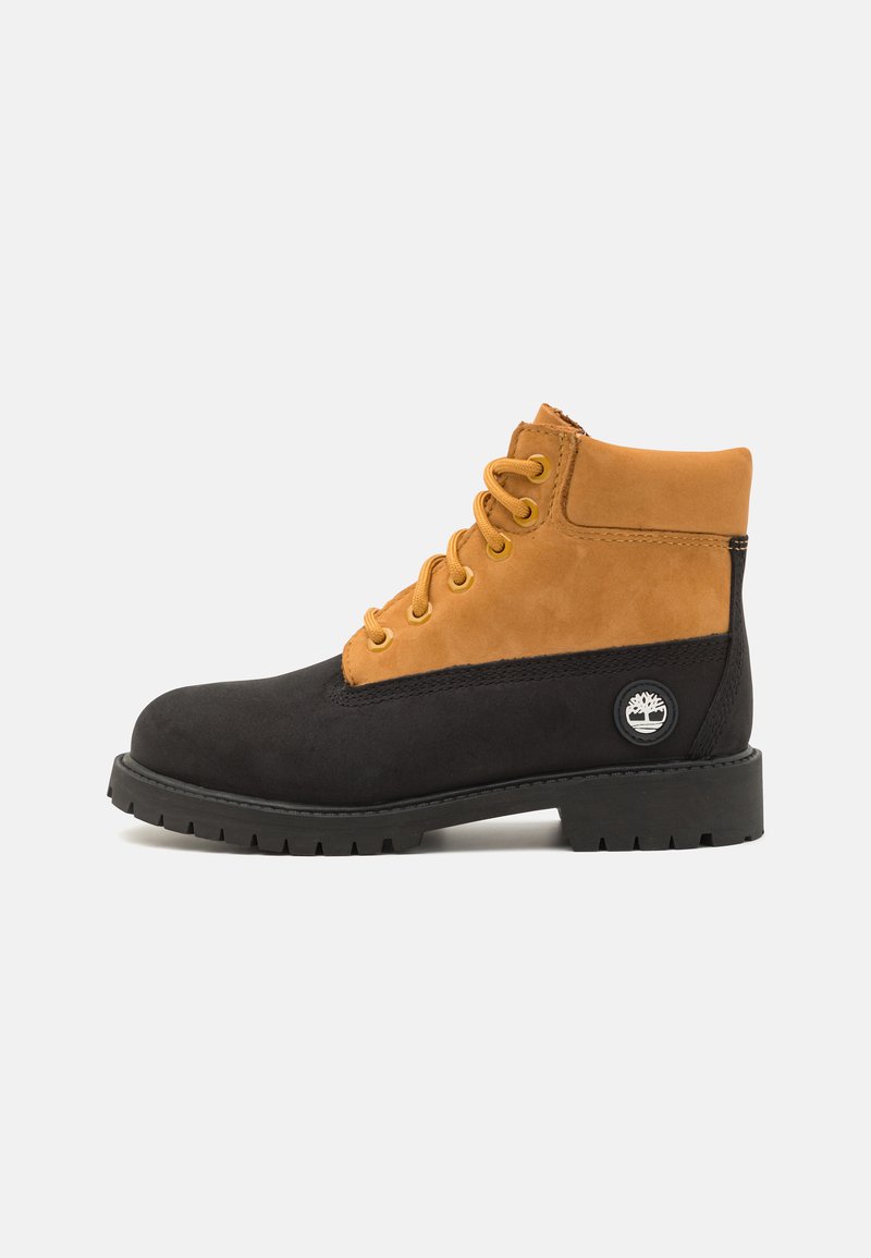 Stivale alla caviglia nero e marrone con tomaia in suede, punta rotonda e suola in gomma. Presenta lacci gialli e un dettaglio del logo brandizzato sul lato.