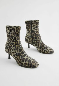Ankle boty s leopardím vzorem a elegantním designem, s špičatou špičkou a 6 cm stiletto podpatkem. Vyrobeno z umělého materiálu se bočním zipem.