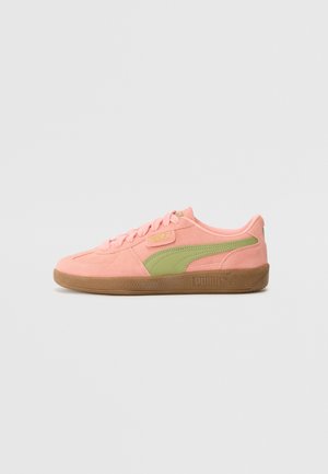 Baskets basses Puma en daim rose avec bande logo vert clair et semelle en gomme sur fond neutre.