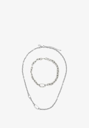 Set di gioielli in metallo argentato composto da una collana lunga e un bracciale corto, entrambi con maglie intrecciate e chiusure a gancio.
