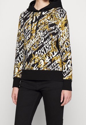 Hooded sweatshirt featuring a gold and black ornate pattern with white text accents. Material is fabric, with ribbed black cuffs and bottom hem.