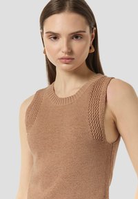 Beżowy, bezrękawnikowy top z dzianiny, z prążkowanym okrągłym dekoltem i teksturowanym wzorem wzdłuż ramion. Miękka, przewiewna tkanina.