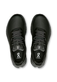Schwarze Sportschuhe mit einem strukturierten Mesh-Obermaterial, runder Zehenpartie, flachen Schnürsenkeln und einer Gummisohle. Auf der Innensohle befindet sich ein auffälliges Logo.