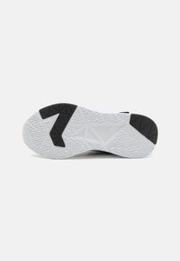 Semelle de chaussure de sport en noir et blanc présentant une surface en caoutchouc texturé avec un motif géométrique et des éléments de traction distincts.
