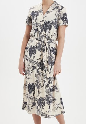 Sukienka z krótkim rękawem i kołnierzykiem w kremowym kolorze z niebieskim nadrukiem drzewa i krajobrazu. Zawiera wiązanie w talii oraz zwiewną, sięgającą połowy łydki spódnicę.