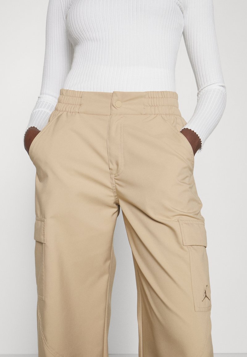Pantaloni cargo beige con elastico in vita, tasche laterali e dettaglio logo ricamato. Realizzati in un tessuto liscio e resistente.