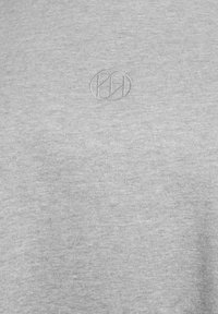 Lichtgrijze sweatshirt gemaakt van een zacht materiaal, met een reliëf logo detail en een subtiel glinsterend patroon over het oppervlak.