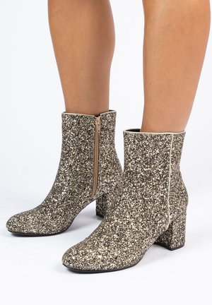 Glanzende enkelboots met een vierkante neus, bedekt met gouden en zilveren pailletten, met een zijrits en een stevige hak.