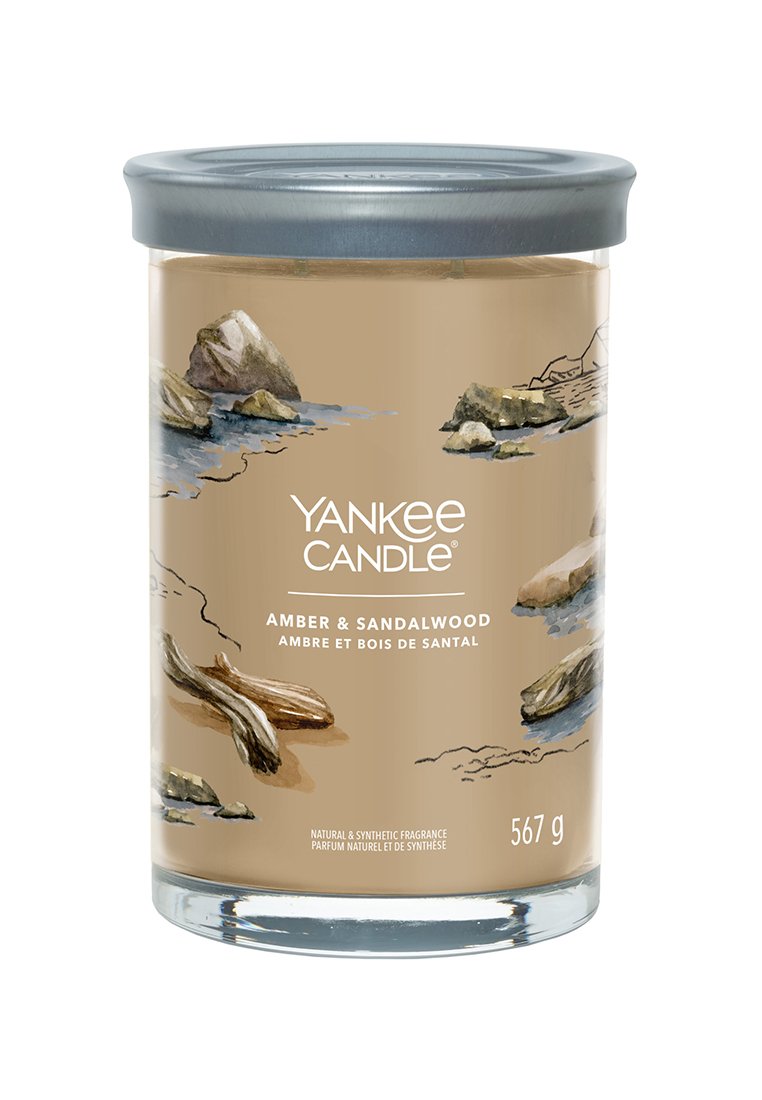 Yankee Candle in einem klaren Glasbehälter mit einem beigen Etikett, das Steine und Treibholz darstellt, beschriftet "Amber & Sandelholz", 567 g.