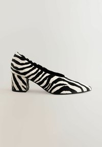Black and white zebra-patterned high heel shoe with a pointed toe and block heel. Made of textured material with a smooth finish.