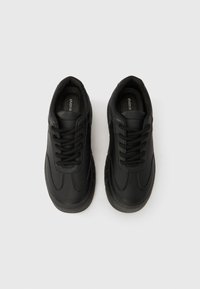 Fekete sportcipő sima bőr felsőrésszel, kerek orral, lapos fűzőkkel, párnázott szegéllyel és texturált gumitalppal; minimalista kialakítás.