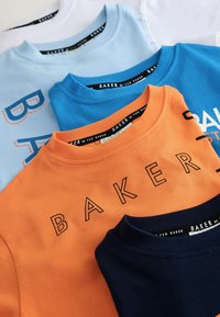 Neli T-särki, mis on laotatud laiali: valge, hele sinine, sinine ja oranž, kus on musta värvi "BAKER" tekst, valmistatud pehmest puuvillast ja ümarate kaelustega.