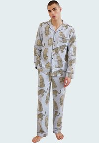 Conjunto de pijama de algodón con un fondo azul claro y un patrón de estampado de leopardo. La parte superior tiene un bolsillo en el pecho y cierre de botones.