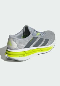 Chaussure de course Adidas grise avec des bandes noires, des accents jaune néon sur la semelle, et un marquage "ADISTAR" et "REPETITOR" sur le côté et le talon.
