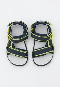 Marinblå sandaler med gula detaljer, försedda med justerbara remmar och en texturerad sula. Lättviktigt material utformat för komfort och stöd.
