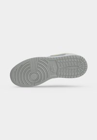 Σόλα από γκρίζο αθλητικό παπούτσι Nike που δείχνει κυκλικά και ορθογώνια σχέδια πέλματος με το λογότυπο Nike ανάγλυφο κοντά στη μέση.