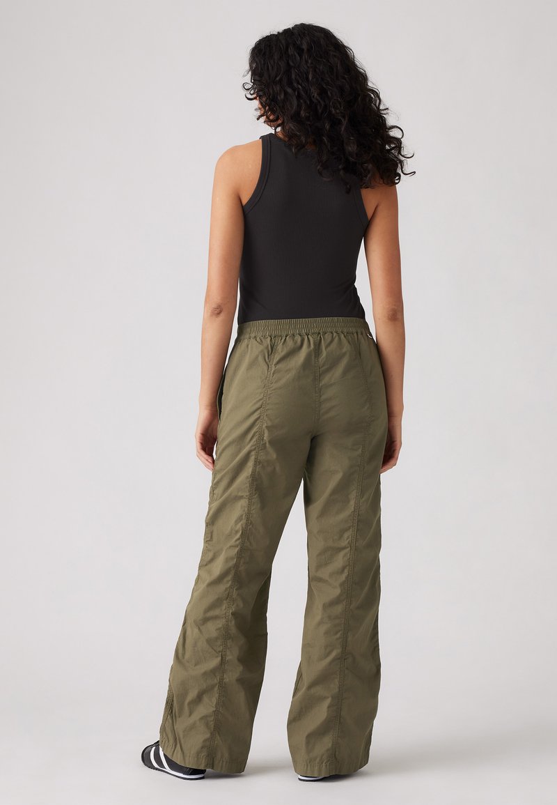 Pantalon vert, ample, en tissu léger, avec une taille élastique et des coutures latérales, associé à un haut sans manches noir.