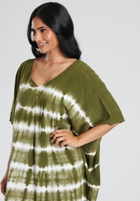 Túnica de decoloración en verde oliva con mangas anchas y escote en V. Presenta rayas blancas y una textura fluida, ideal para el uso diario.