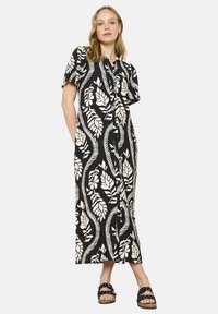 Abito maxi floreale bianco e nero con maniche corte, chiusura con bottoni sul davanti e tasche. Presenta un design a motivi con foglie.
