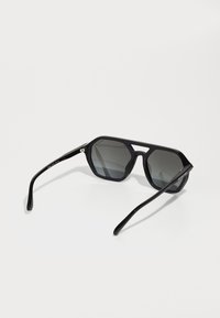 Ochelari de soare negri, octagonali, cu lentile gri; cadru din plastic elegant, cu design geometric; brațe subțiri; detalii subtile ale mărcii pe tâmplă.