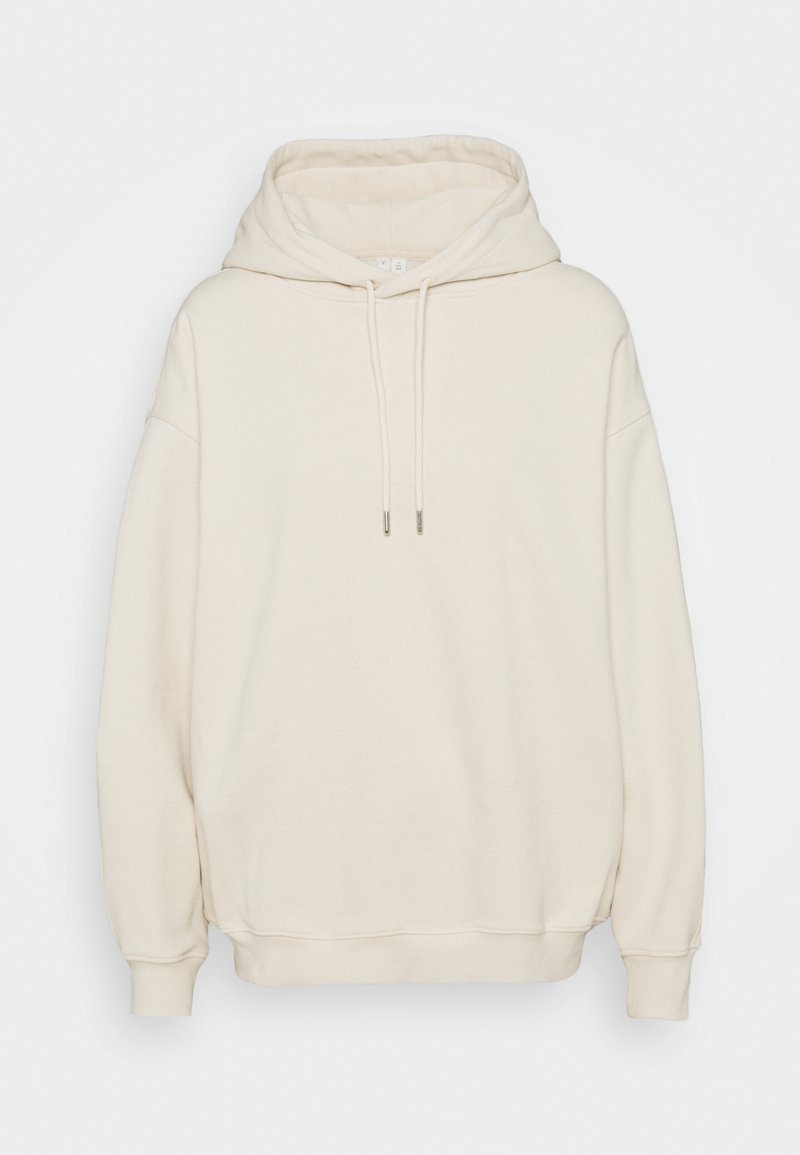 Sudadera color crema fabricada en un material suave, con una capucha grande, cordones y un ajuste holgado. Presenta puños y dobladillo acanalados.