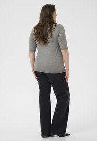 Top gris de manga corta combinado con jeans anchos negros. La tela parece suave, mientras que los jeans tienen una textura clásica de mezclilla.