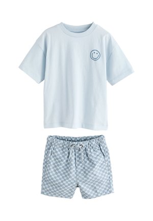 Tricou albastru deschis cu mâneci scurte și față zâmbitoare mică pe piept, asortat cu șorturi cu șnur, albastre și albe în carouri.
