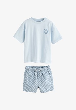 Tricou albastru deschis cu mâneci scurte și față zâmbitoare mică pe piept, asortat cu șorturi cu șnur, albastre și albe în carouri.